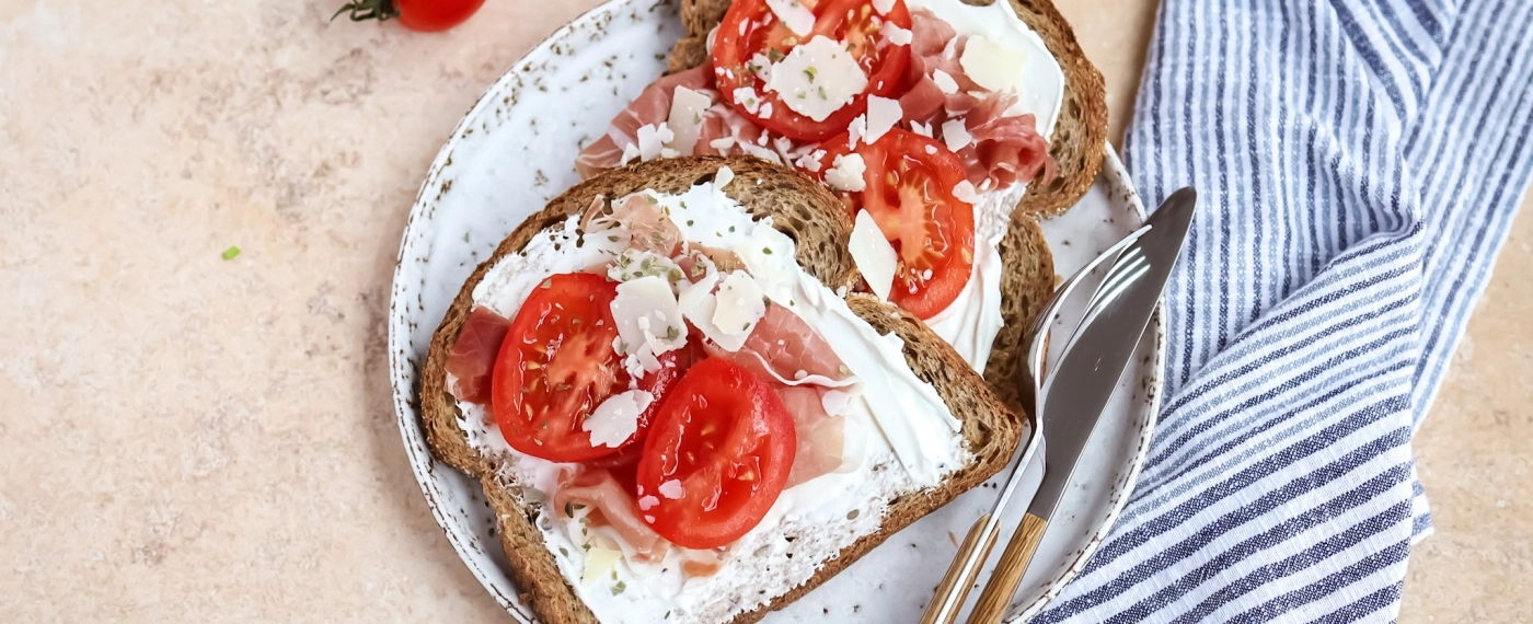Brood met zuivelspread, rauwe ham, tomaat & geraspte kaas