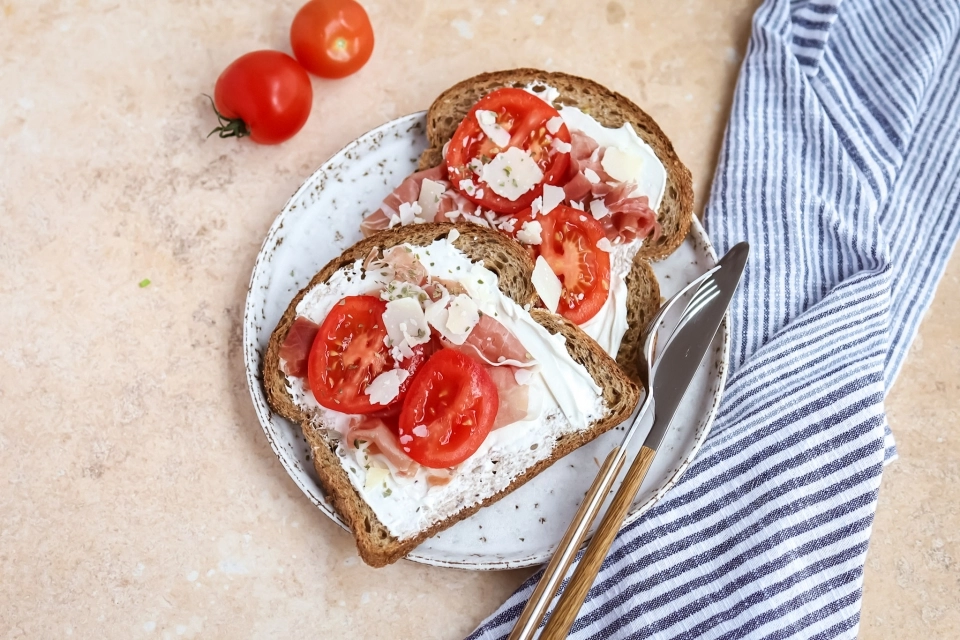 Brood met zuivelspread, rauwe ham, tomaat & geraspte kaas